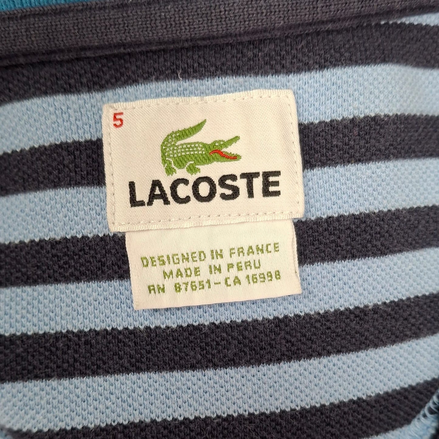 Camiseta Polo Lacoste 🐊 color celeste y diseño en cuello y manga color azul Talla L Entalle Regular