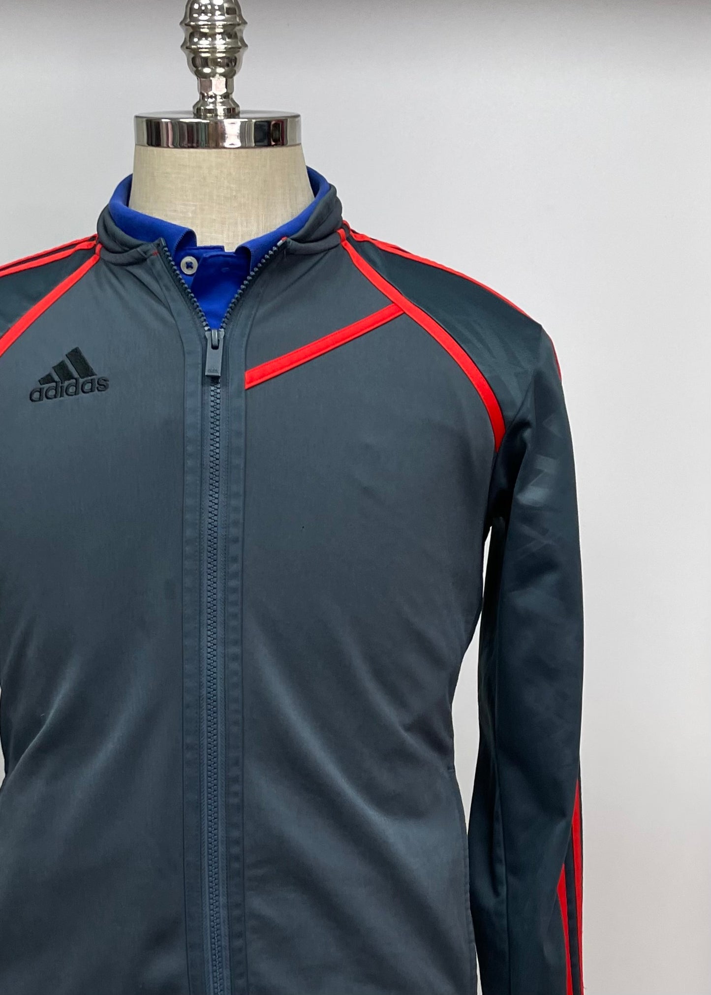 Jacket Adidas 🏃🏻‍♂️ color gris oscuro con rayas en naranja con zíper completo y logo en color negro Talla M