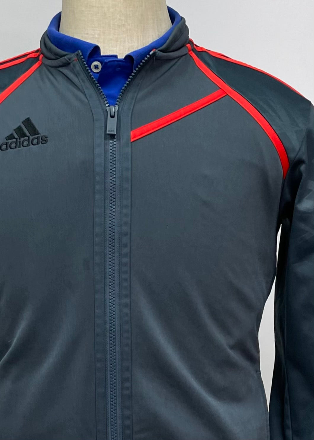 Jacket Adidas 🏃🏻‍♂️ color gris oscuro con rayas en naranja con zíper completo y logo en color negro Talla M