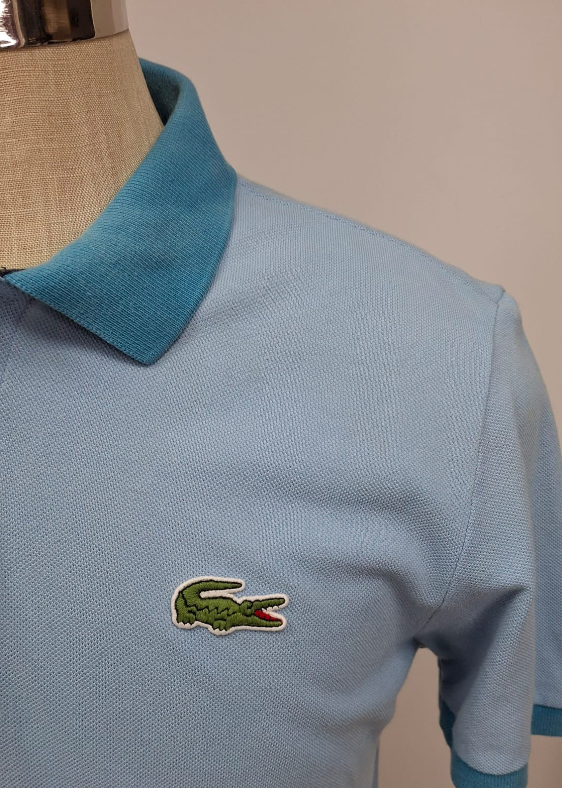 Camiseta Polo Lacoste 🐊 color celeste y diseño en cuello y manga color azul Talla L Entalle Regular