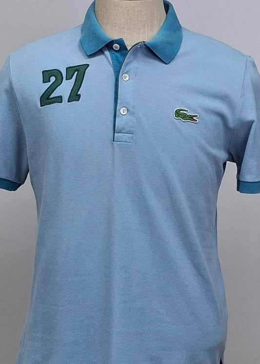 Camiseta Polo Lacoste 🐊 color celeste y diseño en cuello y manga color azul Talla L Entalle Regular