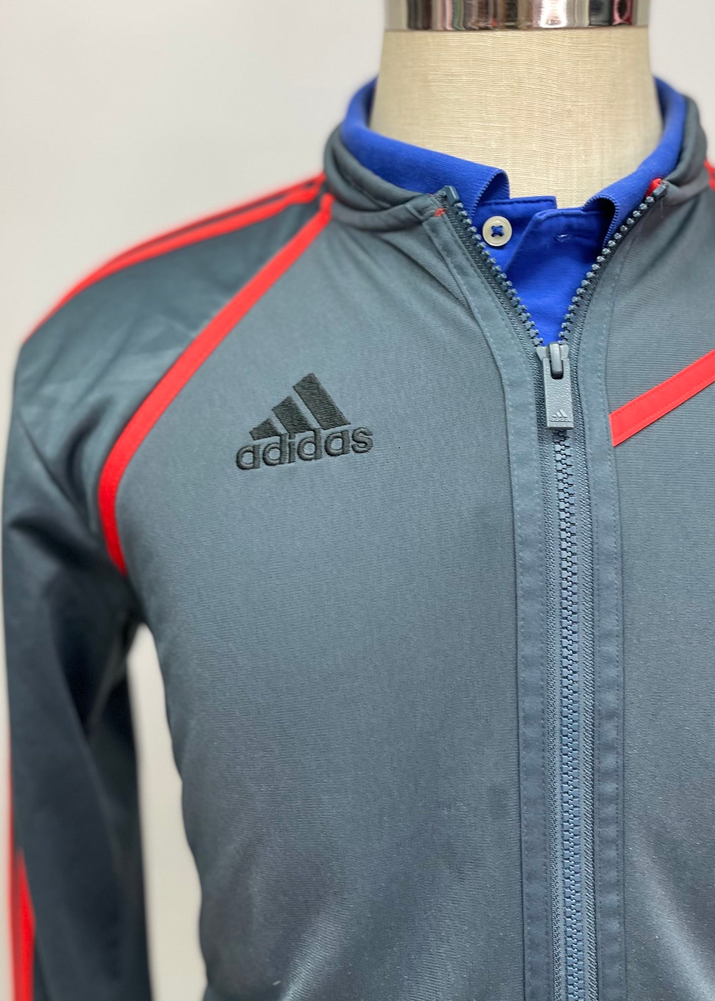 Jacket Adidas 🏃🏻‍♂️ color gris oscuro con rayas en naranja con zíper completo y logo en color negro Talla M