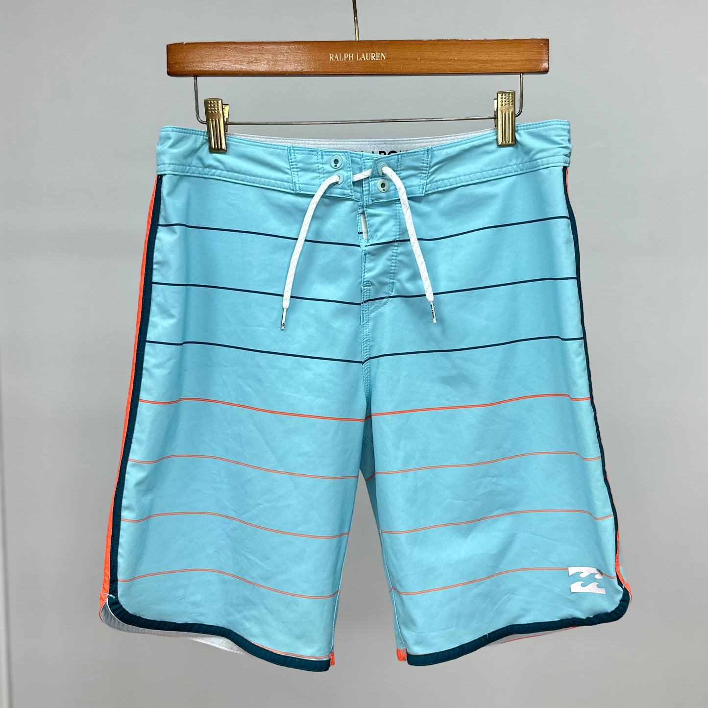 Short de baño Billabong 🏄🏽‍♂️ color celeste con patron de rayas en negro y naranja con logo en color blanco Talla S