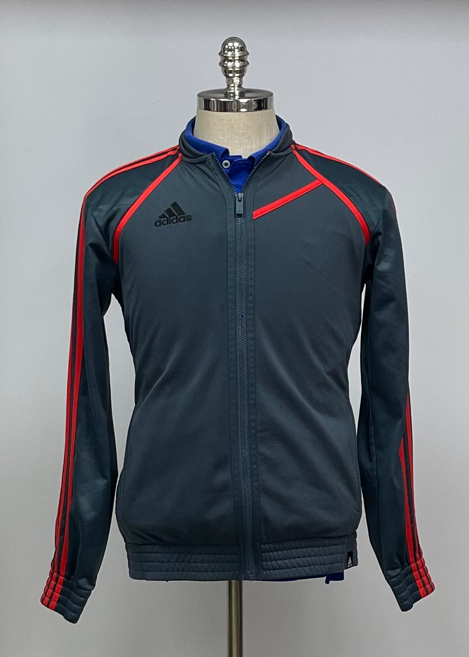 Jacket Adidas 🏃🏻‍♂️ color gris oscuro con rayas en naranja con zíper completo y logo en color negro Talla M