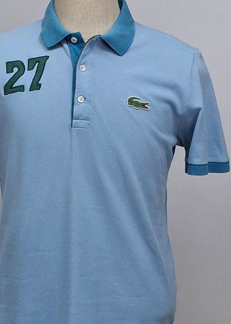 Camiseta Polo Lacoste 🐊 color celeste y diseño en cuello y manga color azul Talla L Entalle Regular
