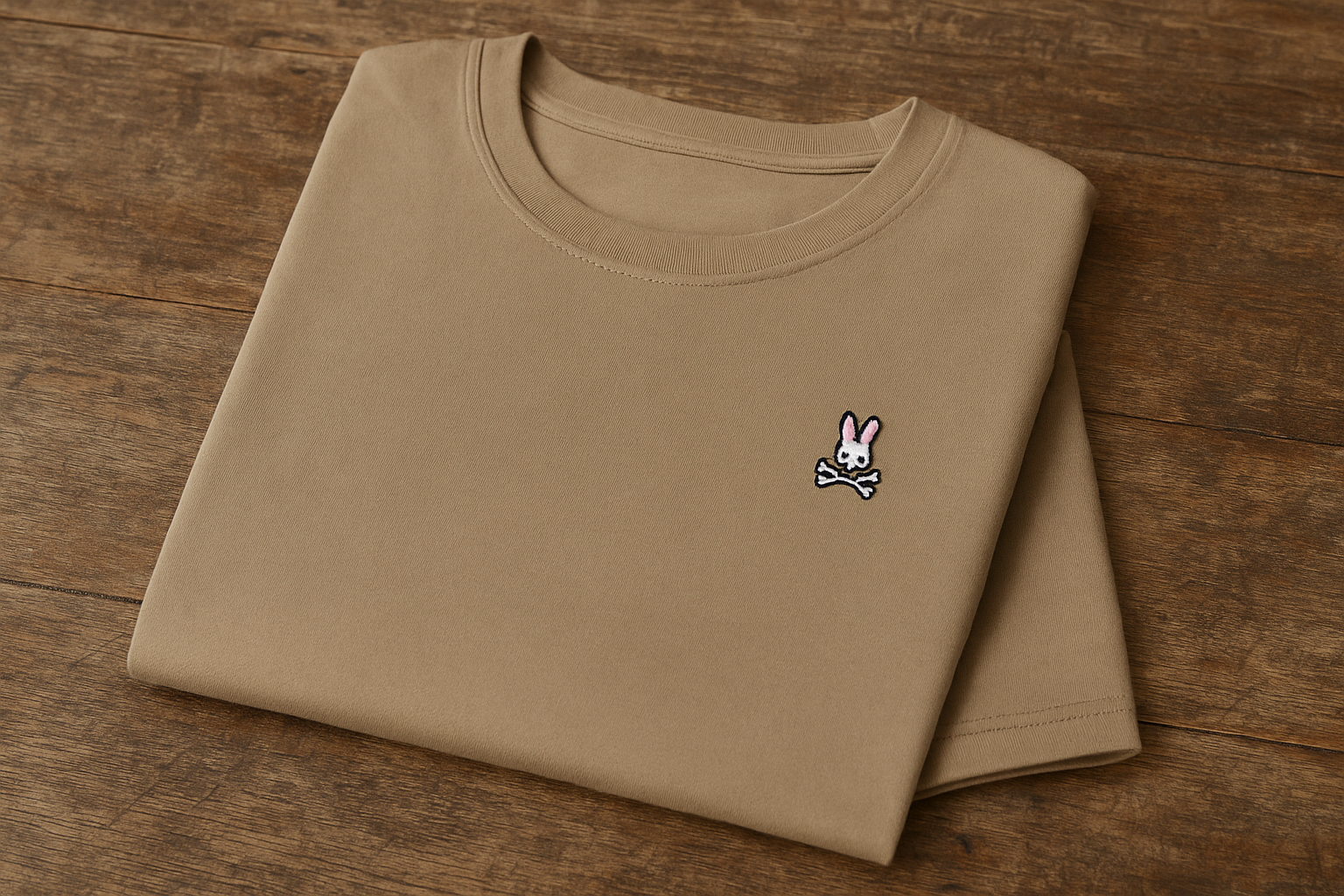 Camiseta Psycho Bunny beige - Doblada en superficie de madera