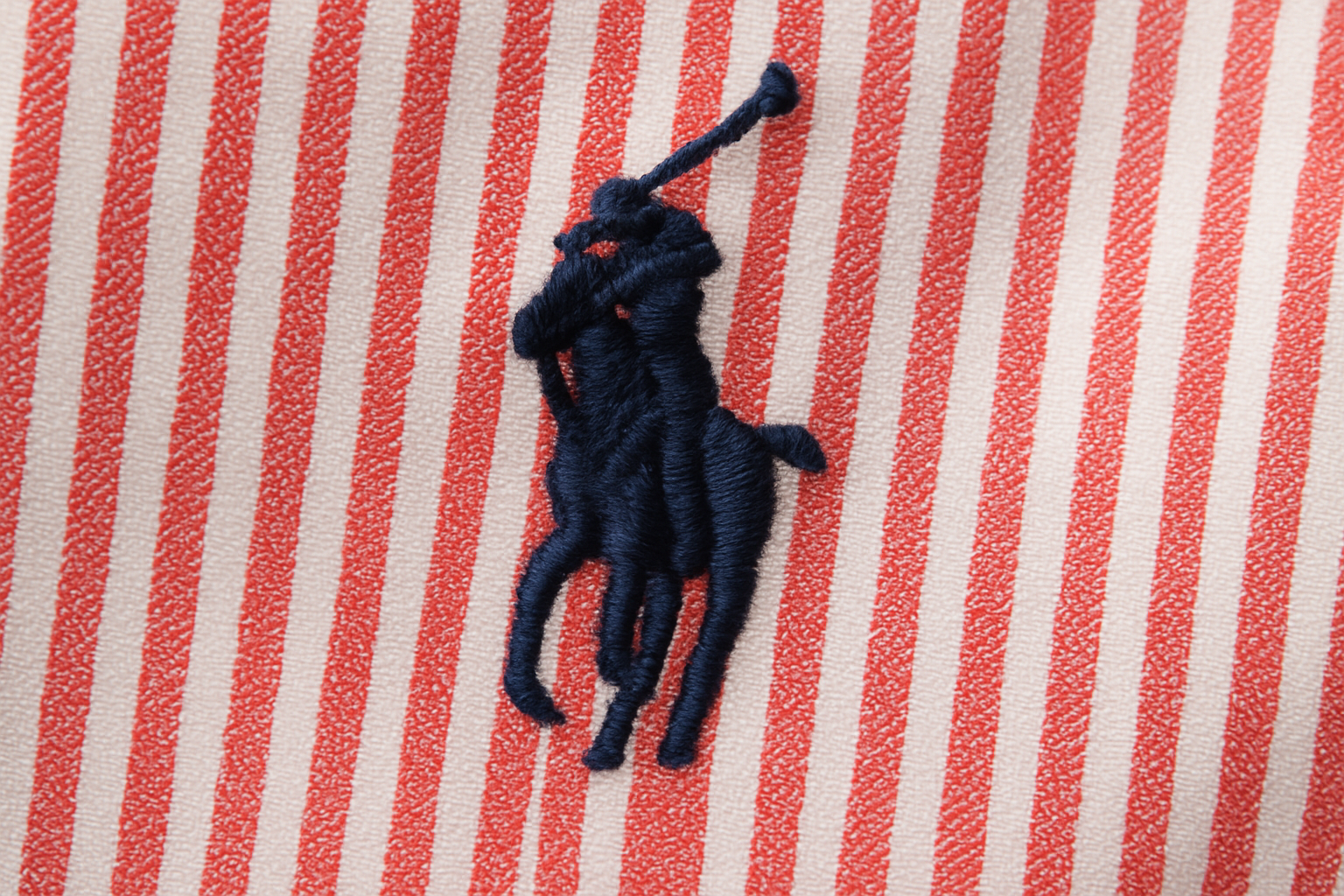 Detalle logo azul navy sobre rayas rojas y blancas